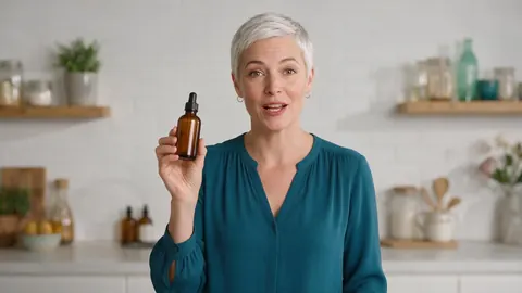 Presenter in her 40s holding a skincare bottle and speaking to camera in a bright studio