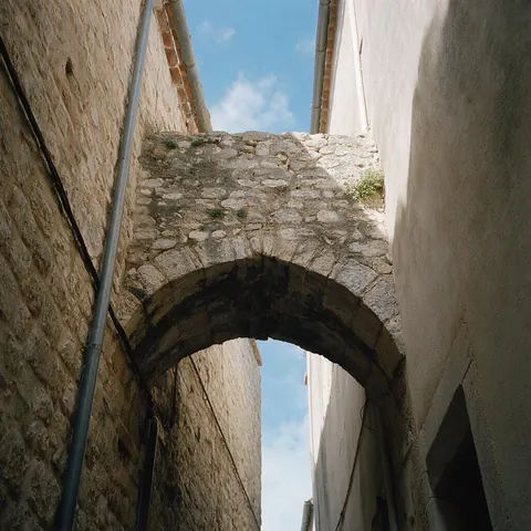 Low-angle photo of a stone archway in a narrow alley