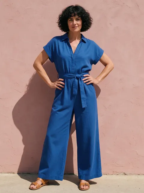 Jumpsuit full-body shot: AI-generated full-body ad of a cobalt wide-leg jumpsuit against a pink wall