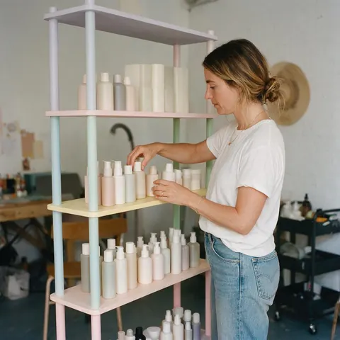Founder arranging unbranded skincare bottles on a shelf