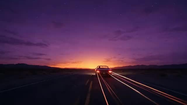 Looping clip: a convertible driving along a desert highway at dusk