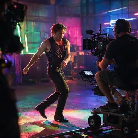 Performer in a neon warehouse filmed by a camera on a dolly