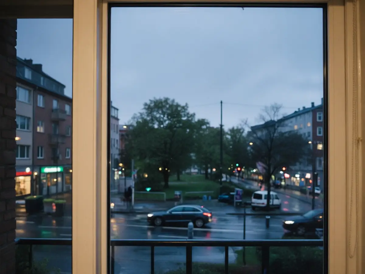 Rainy city street photographed through a window with a lamp and a person reflected in the glass — after