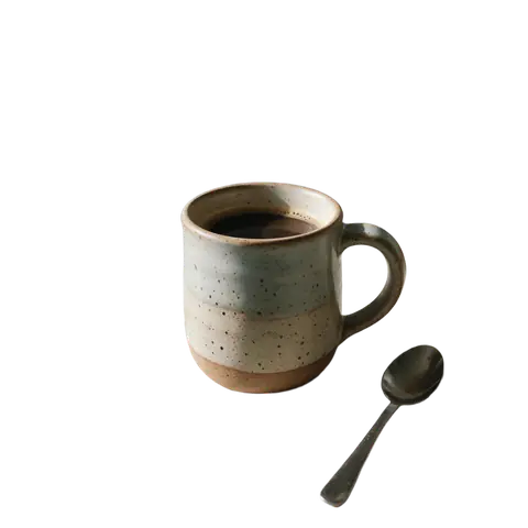 Handmade ceramic mug on a messy kitchen counter