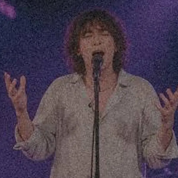 Singer on a small club stage under purple and blue lights — the 720 px, heavy noise original stretched to the same size (bicubic)