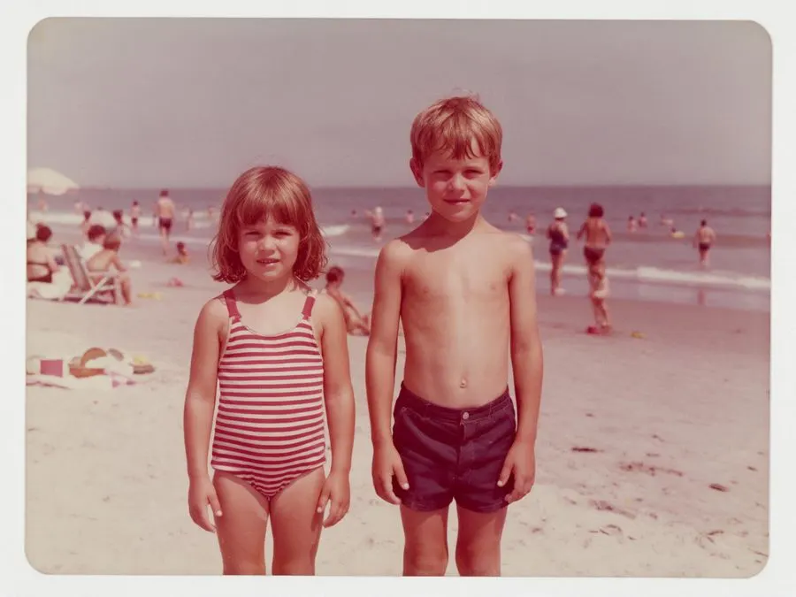 Faded 1970s colour snapshot of two children on a beach with a red-magenta cast — before
