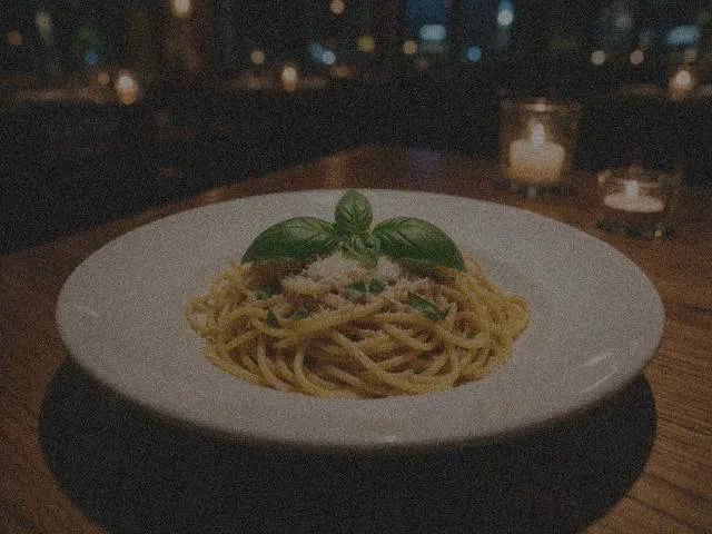 Plate of pasta with basil in a dim candle-lit restaurant — before