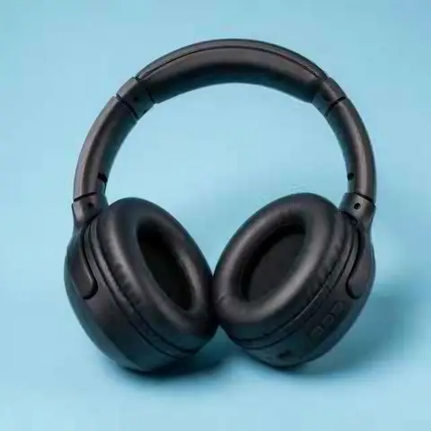 Matte black over-ear wireless headphones on a pastel blue background