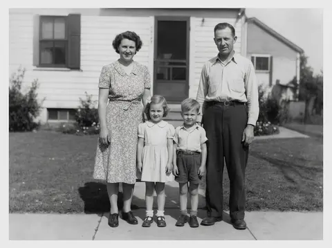 Faded 1950s black-and-white family photo in front of a house, with scratches and a torn corner