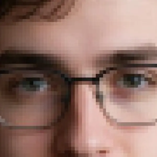 Young man with glasses and a navy hoodie against a brick wall — the 150 px, blown up original stretched to the same size (bicubic)