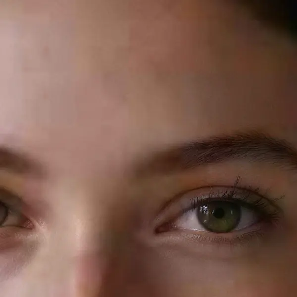 Close-up portrait of a young woman with freckles and dark curly hair — the same crop after Image Upscaler