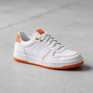 White leather sneaker with orange details on a concrete floor — before