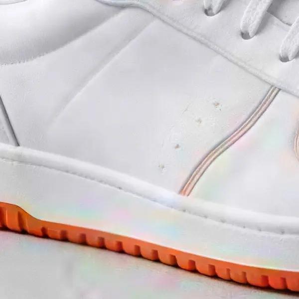 White leather sneaker with orange details on a concrete floor — the same crop after Real-ESRGAN
