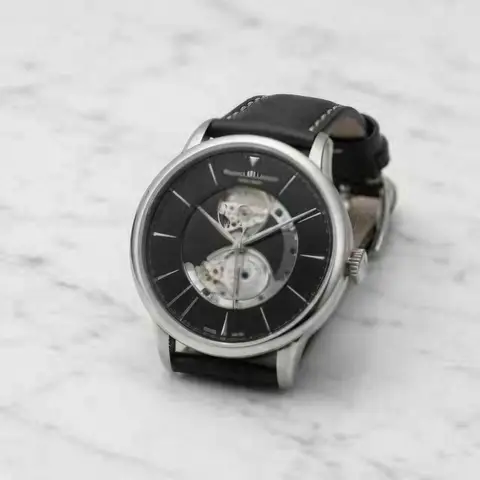 Silver wristwatch with a black leather strap on white marble