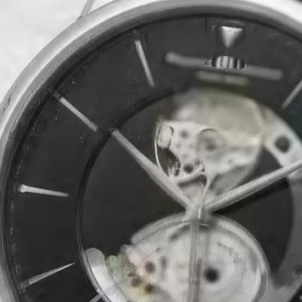 Silver wristwatch with a black leather strap on white marble — the same crop after Image Upscaler